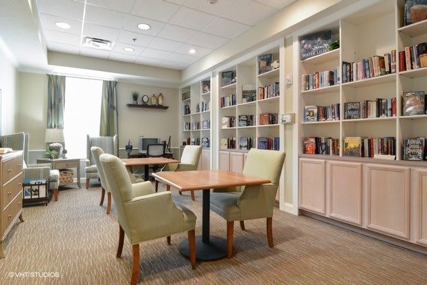 A cozy library with bookshelves, tables, and chairs for reading.
