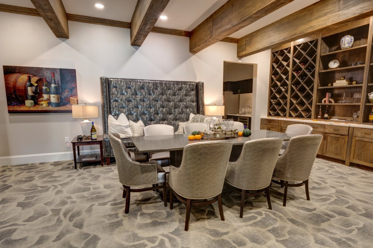 A beautifully designed dining room featuring a large table with cushioned chairs, ambient lighting, and a wooden wine rack.
