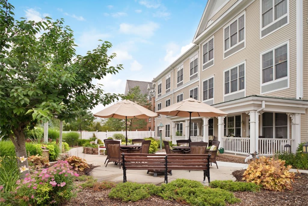 A well-maintained outdoor patio area with benches and umbrellas, adjacent to a multi-story building.