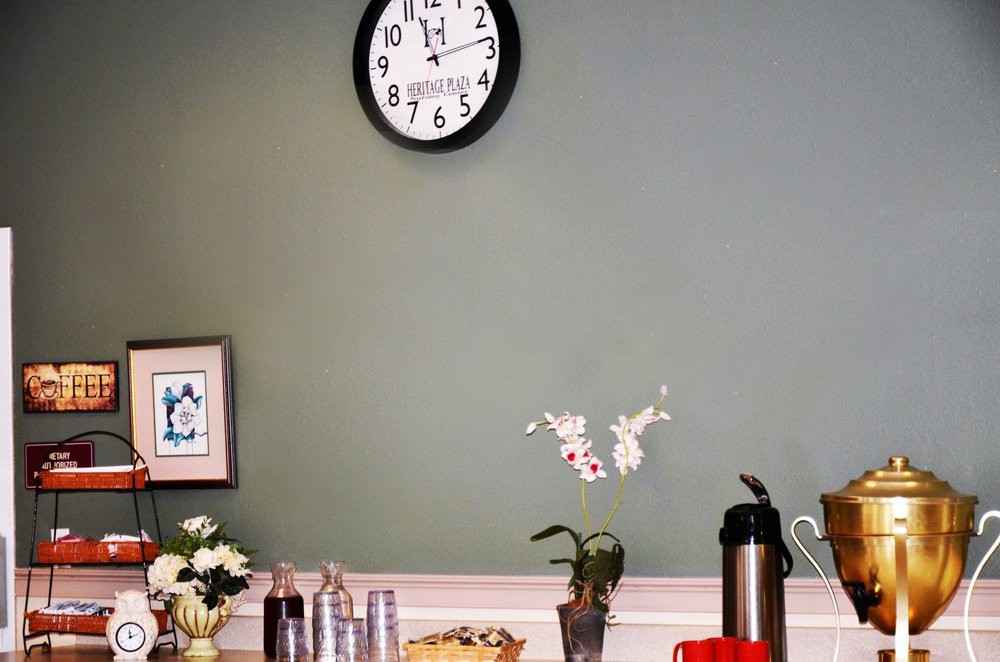 A cozy setup with a wall clock, flowers, and a coffee station on the table.