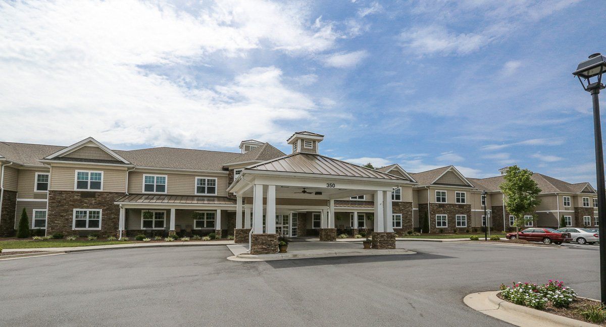 A large building with a prominent entrance and a cloudy sky in the background.