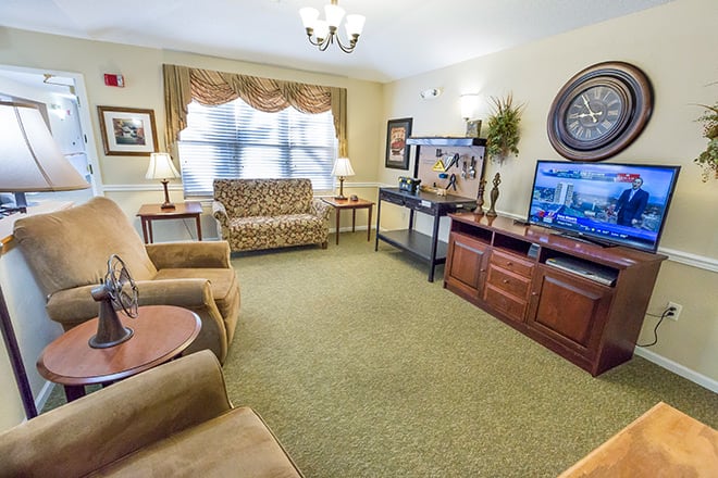 A cozy living room with comfortable seating and two televisions.