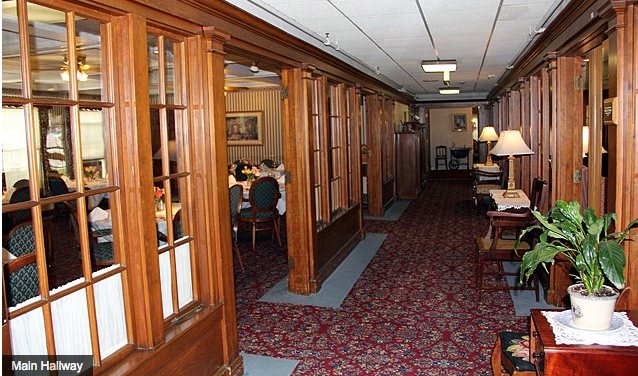 A cozy interior hallway leading to a dining area, featuring wood paneling and a patterned carpet.