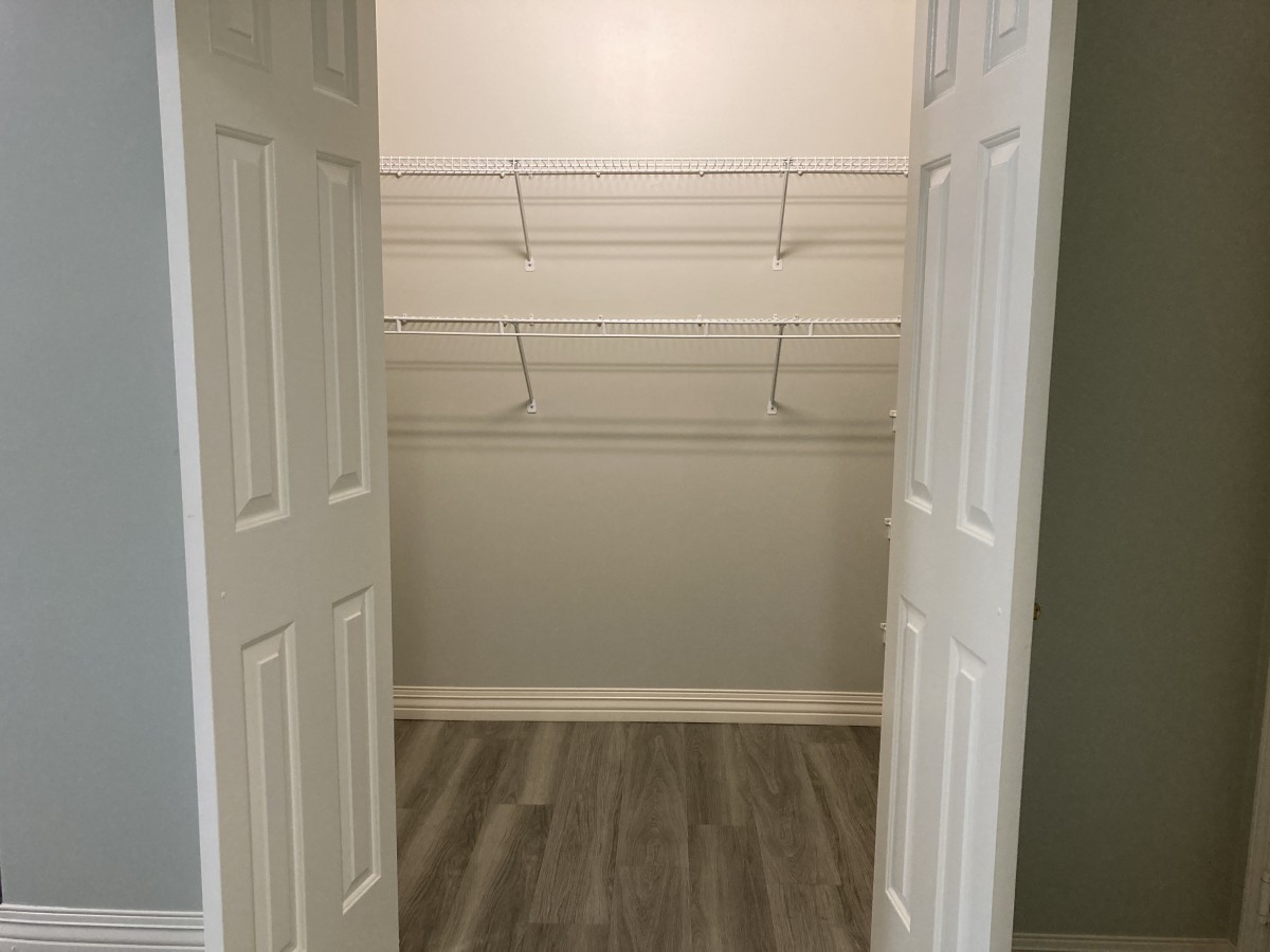 An empty walk-in closet with wire shelving and double doors.