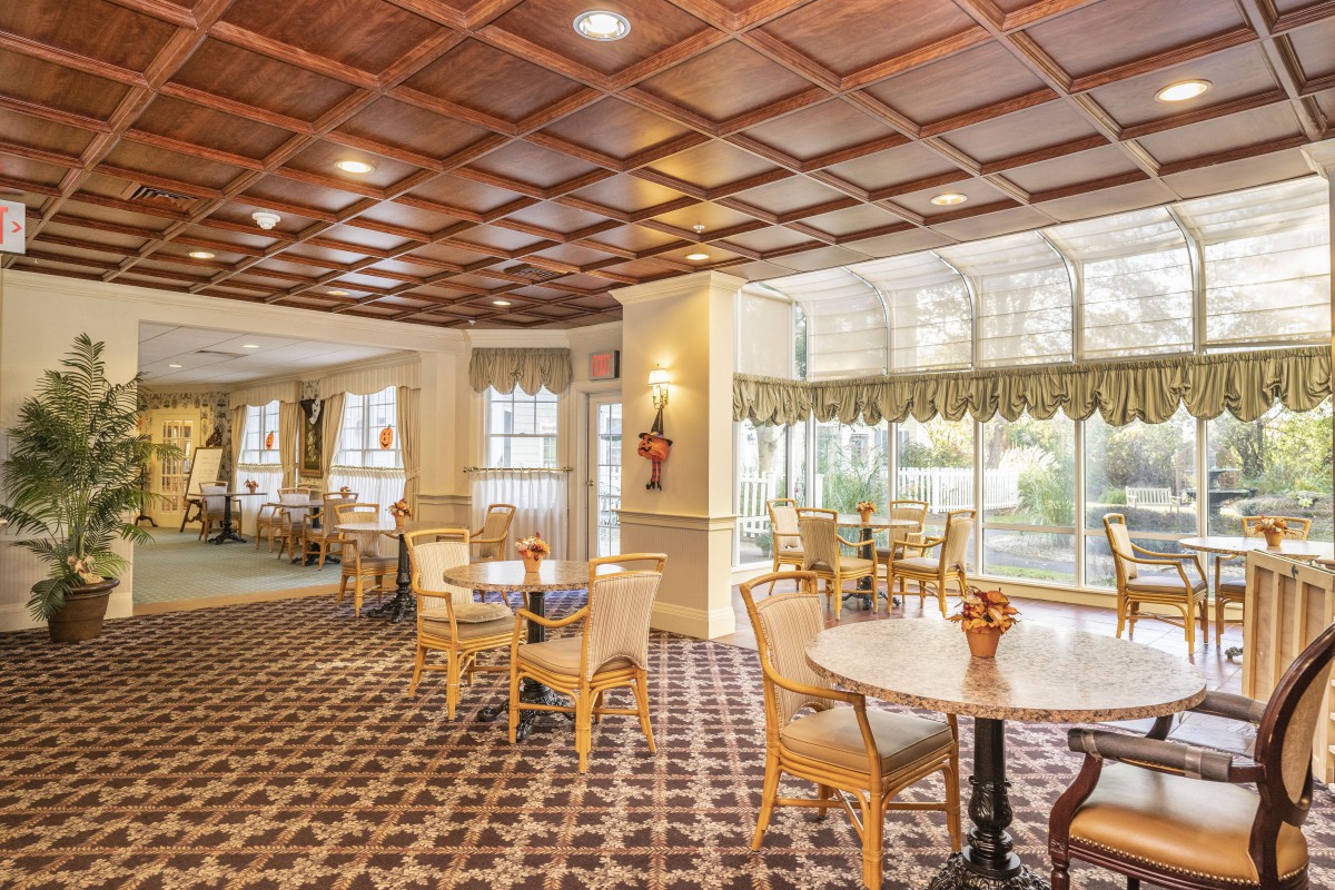 An elegant dining area with wooden chairs, round tables, and a patterned carpet.