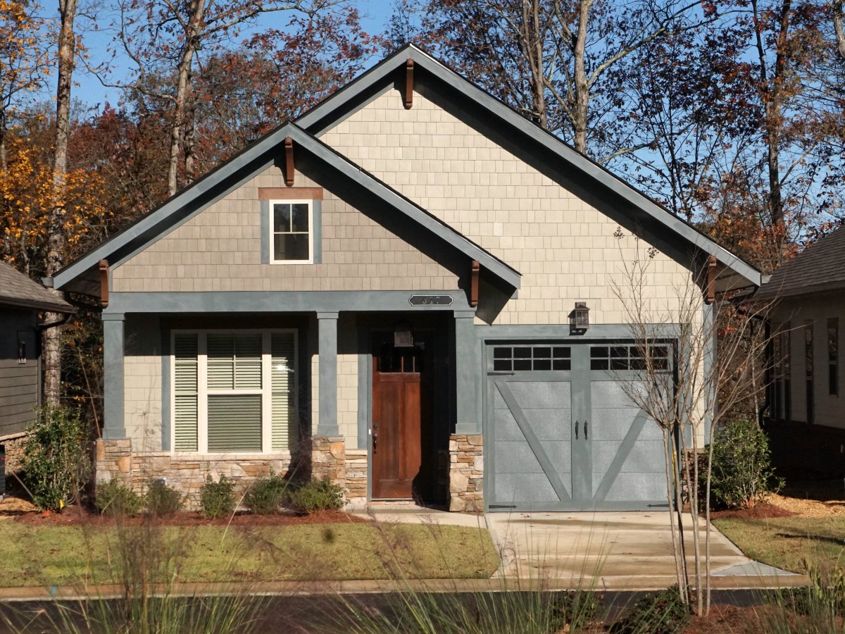 A charming cottage-style house with a single garage and stone accents.
