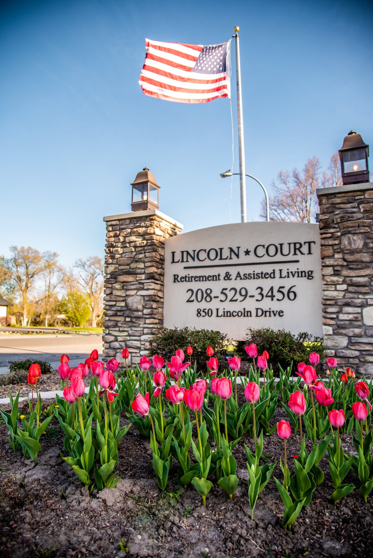 Entrance sign for Lincoln Court Retirement and Assisted Living, surrounded by blooming tulips.