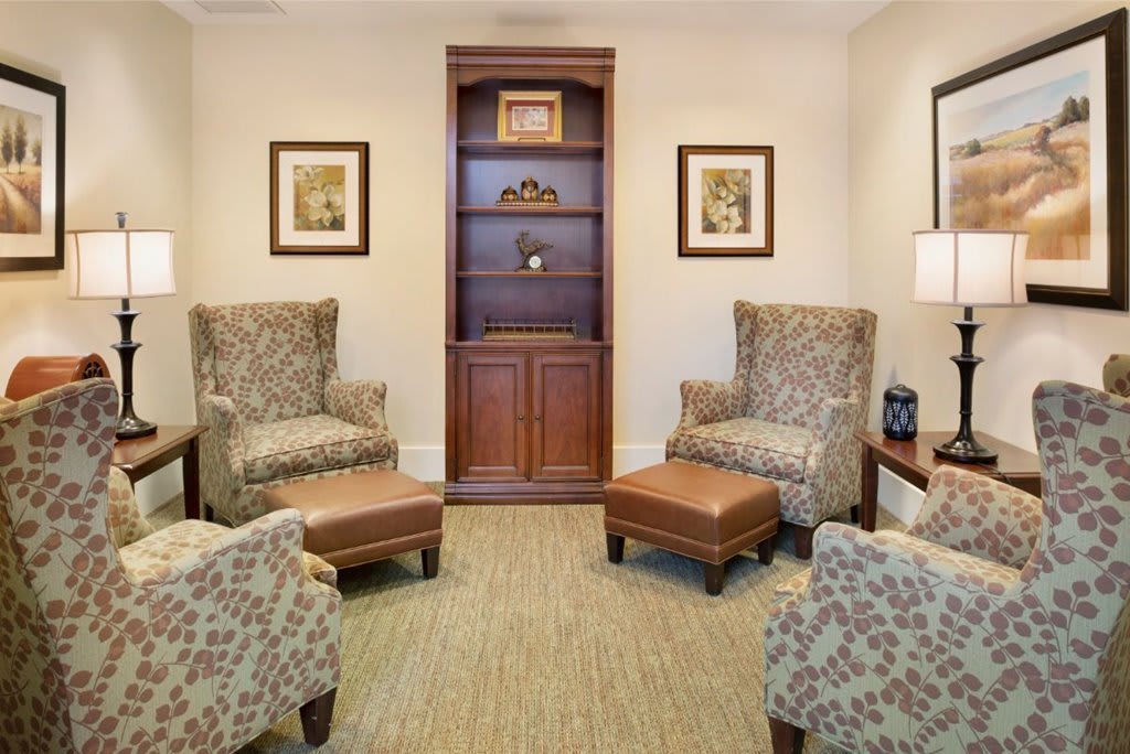 A cozy living room with patterned armchairs and a central bookshelf.