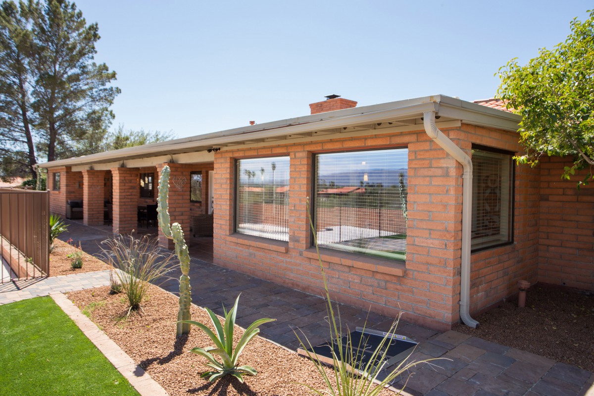 A brick house surrounded by a desert landscape with cacti.