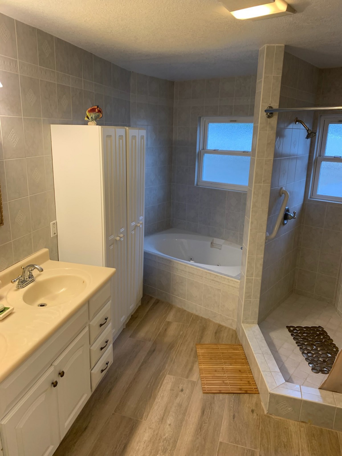 A modern bathroom featuring a bathtub, shower, and sink with a cabinet and mirror.