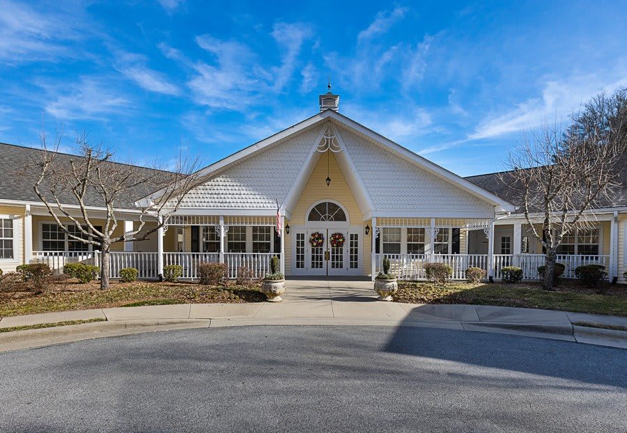 A large white house with a wide porch set against a blue sky.