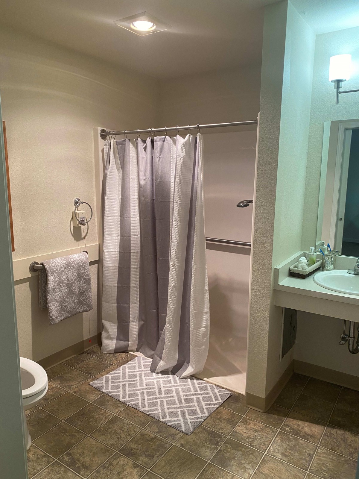 A clean bathroom with a shower curtain, sink, and mirror.