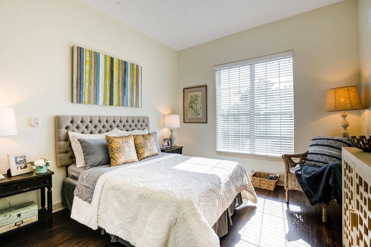 A cozy bedroom with a stylish bed, decorative artwork, and ample natural light from the window.