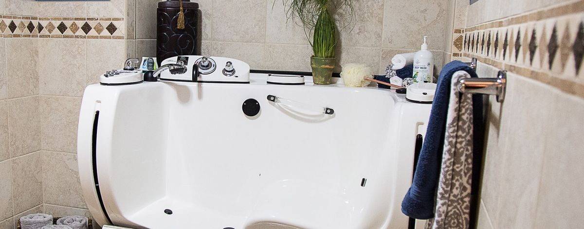 A luxurious bathtub setup with spa features and a potted plant for a relaxing atmosphere.