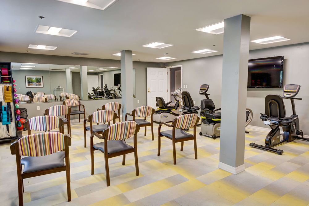 A fitness room with exercise equipment and arranged chairs.
