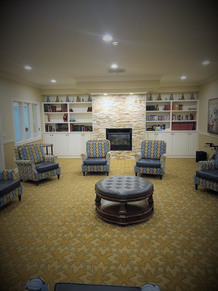 A cozy living room with patterned chairs, a central coffee table, and built-in bookshelves surrounding a fireplace.