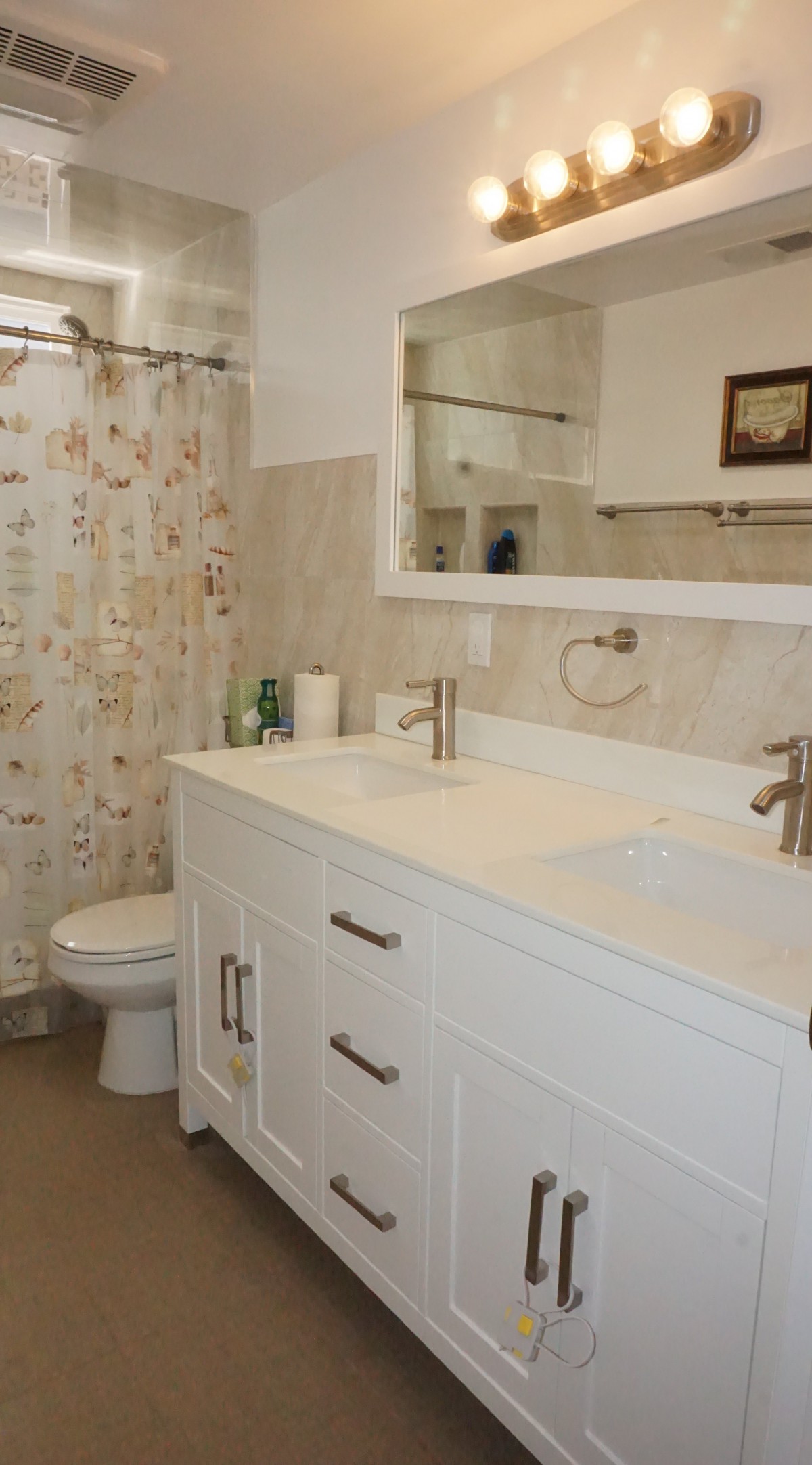 A modern bathroom featuring a double sink vanity, large mirror, and a decorative shower curtain.