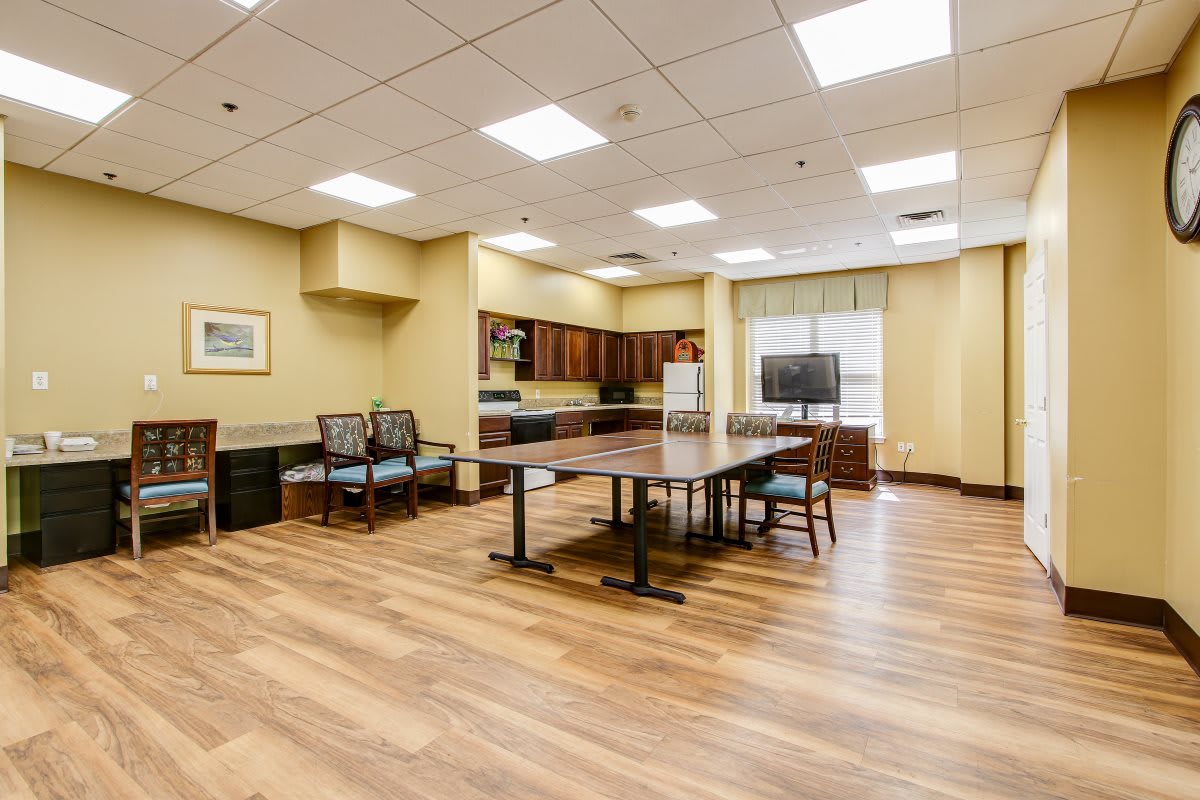 A spacious kitchen and dining area with wooden flooring, featuring a large table, chairs, a television, and ample cabinet space.