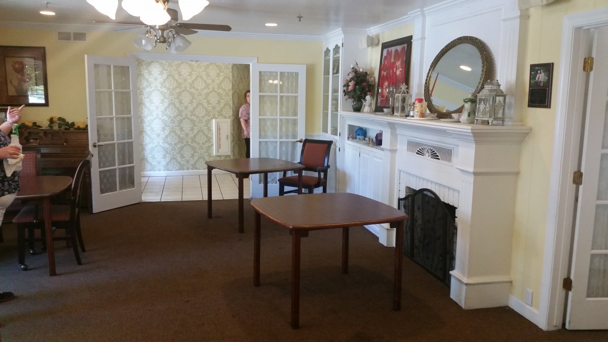 A cozy living room with a fireplace, two tables, a chair, and decorative items.