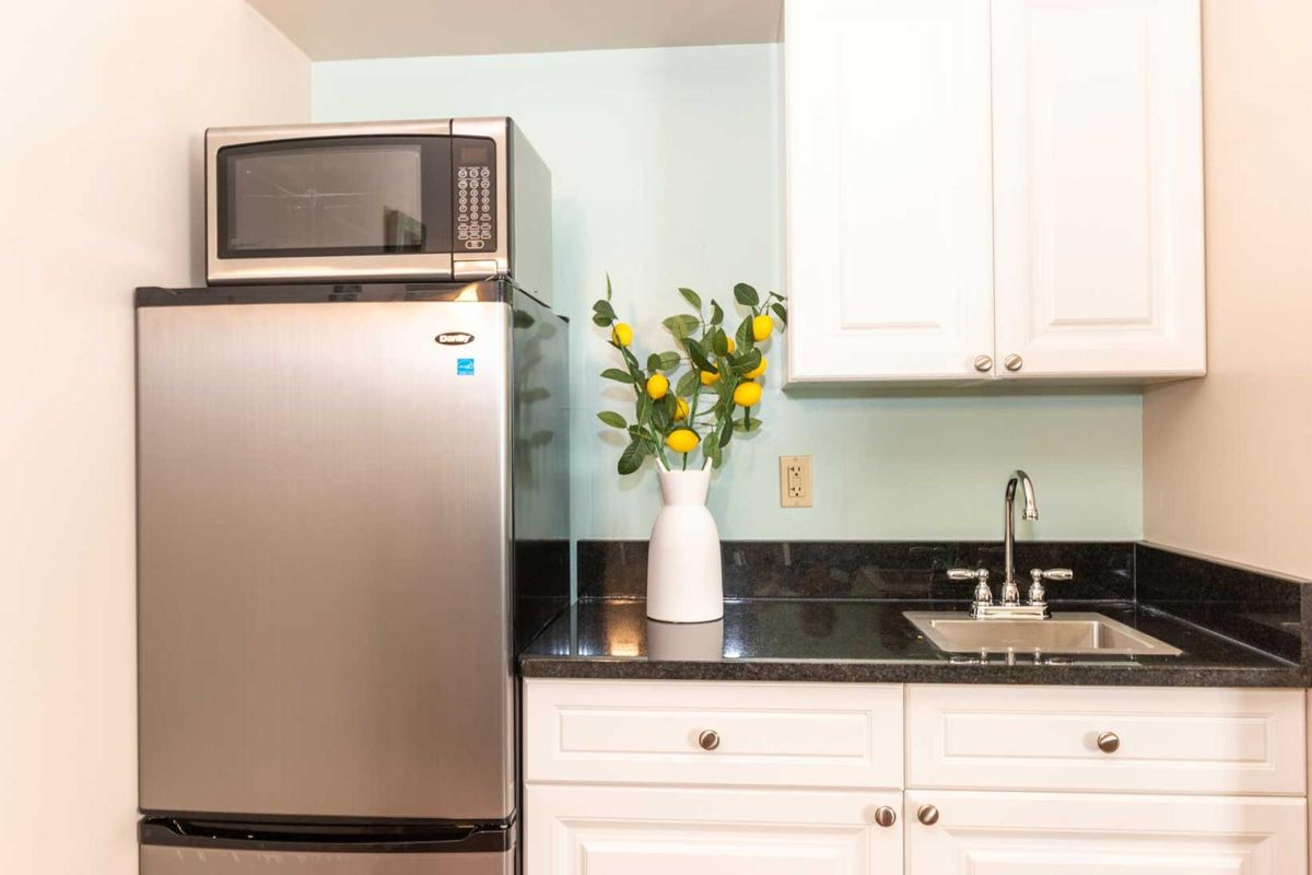 A modern kitchen with stainless steel appliances and a vase of flowers on the counter.