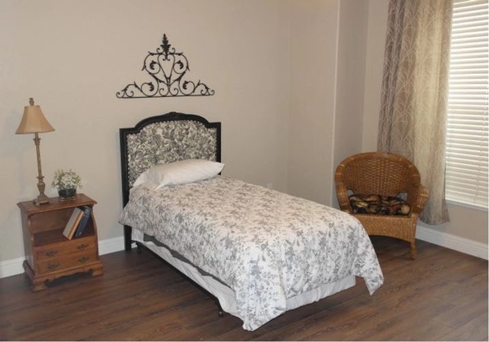 A cozy bedroom with a single decorated bed, featuring patterned bedding and a decorative headboard.