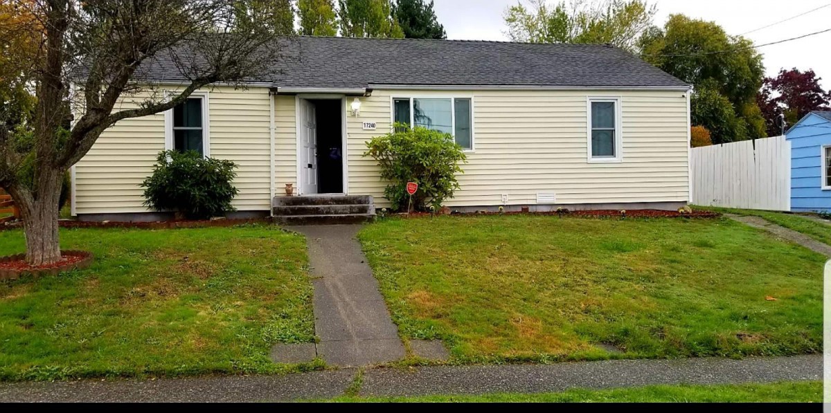 A small single-story house with a front lawn and pathway leading to the entrance on an overcast day.