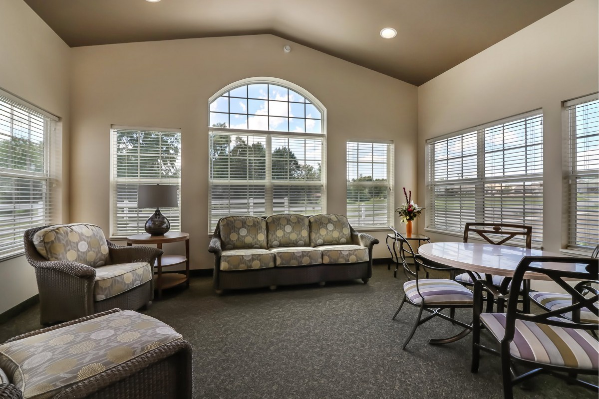 A bright and spacious living room with large windows, comfortable sofas, and a dining table with chairs.
