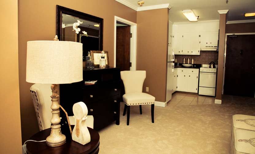 A cozy living area with a view into the kitchen, featuring elegant furniture and warm lighting.