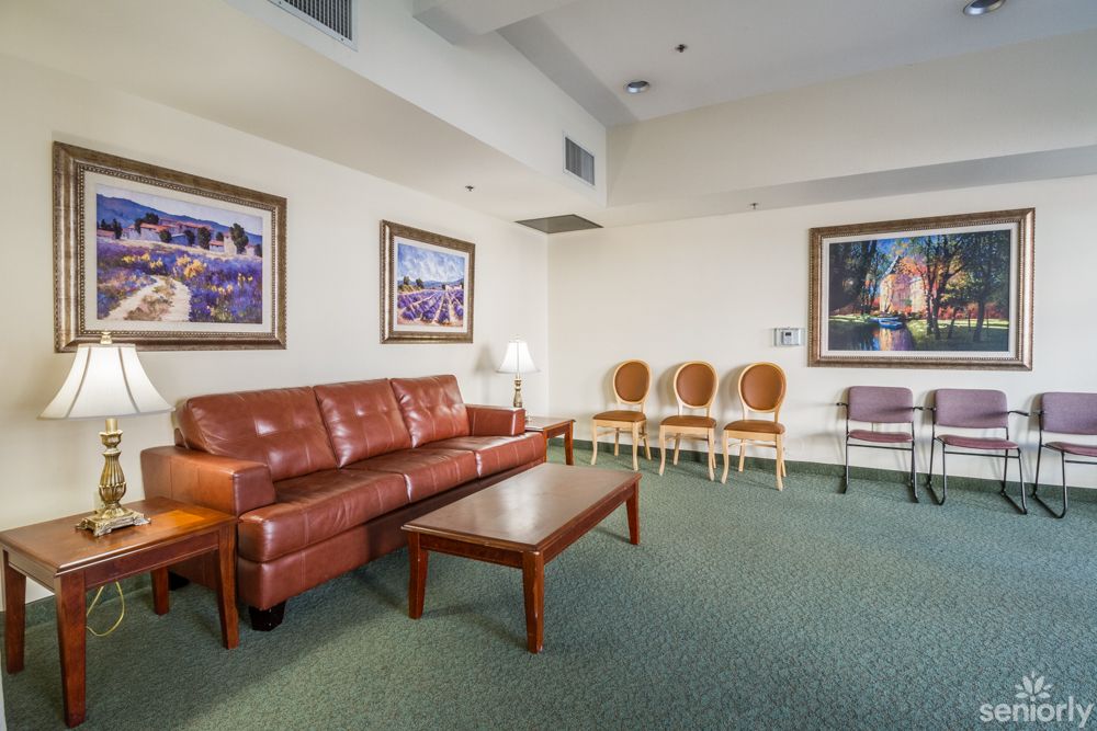 A comfortable waiting room with a leather sofa, wooden chairs, and framed artwork on the walls.