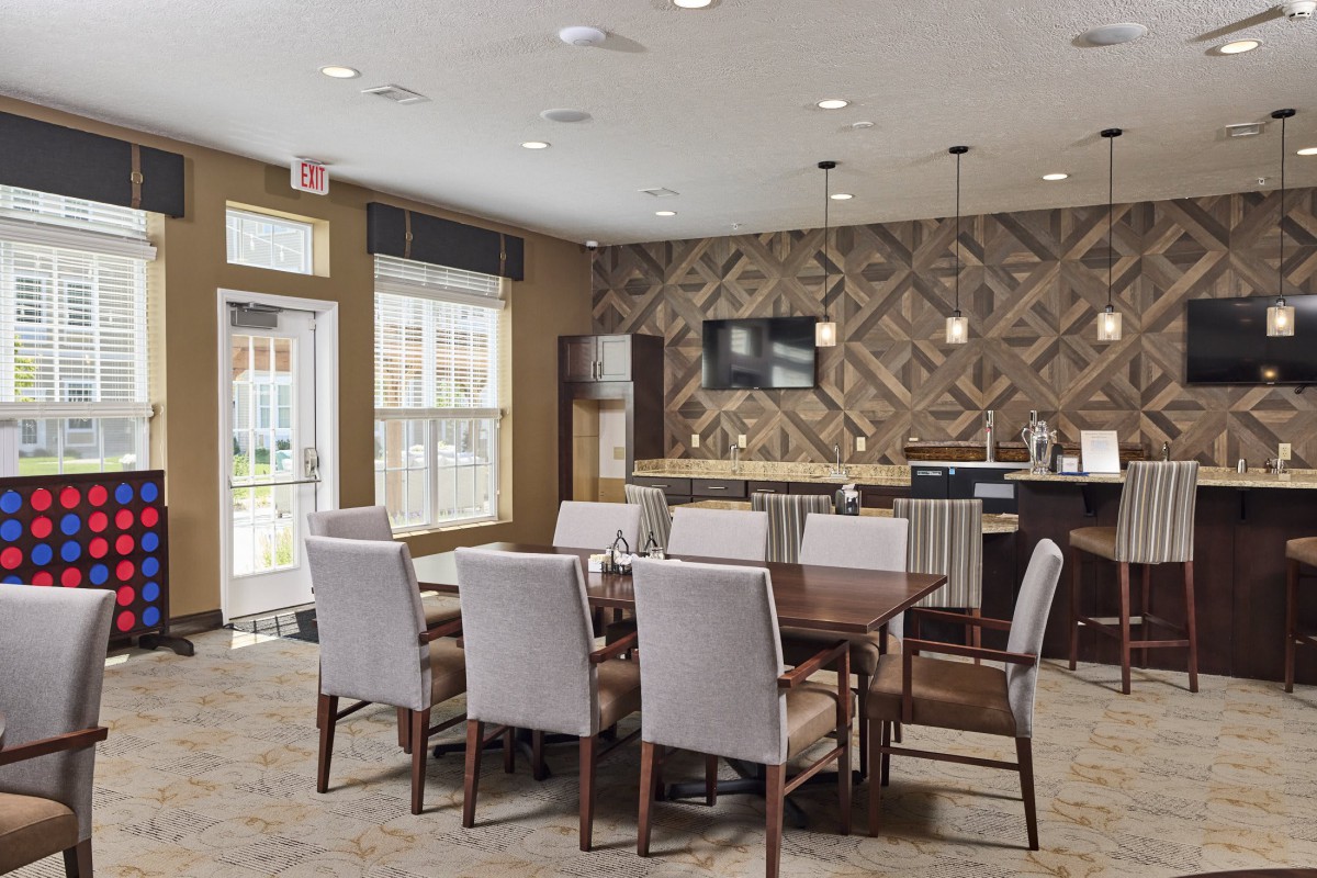 A modern dining area with a wooden table, upholstered chairs, and decorative lighting.