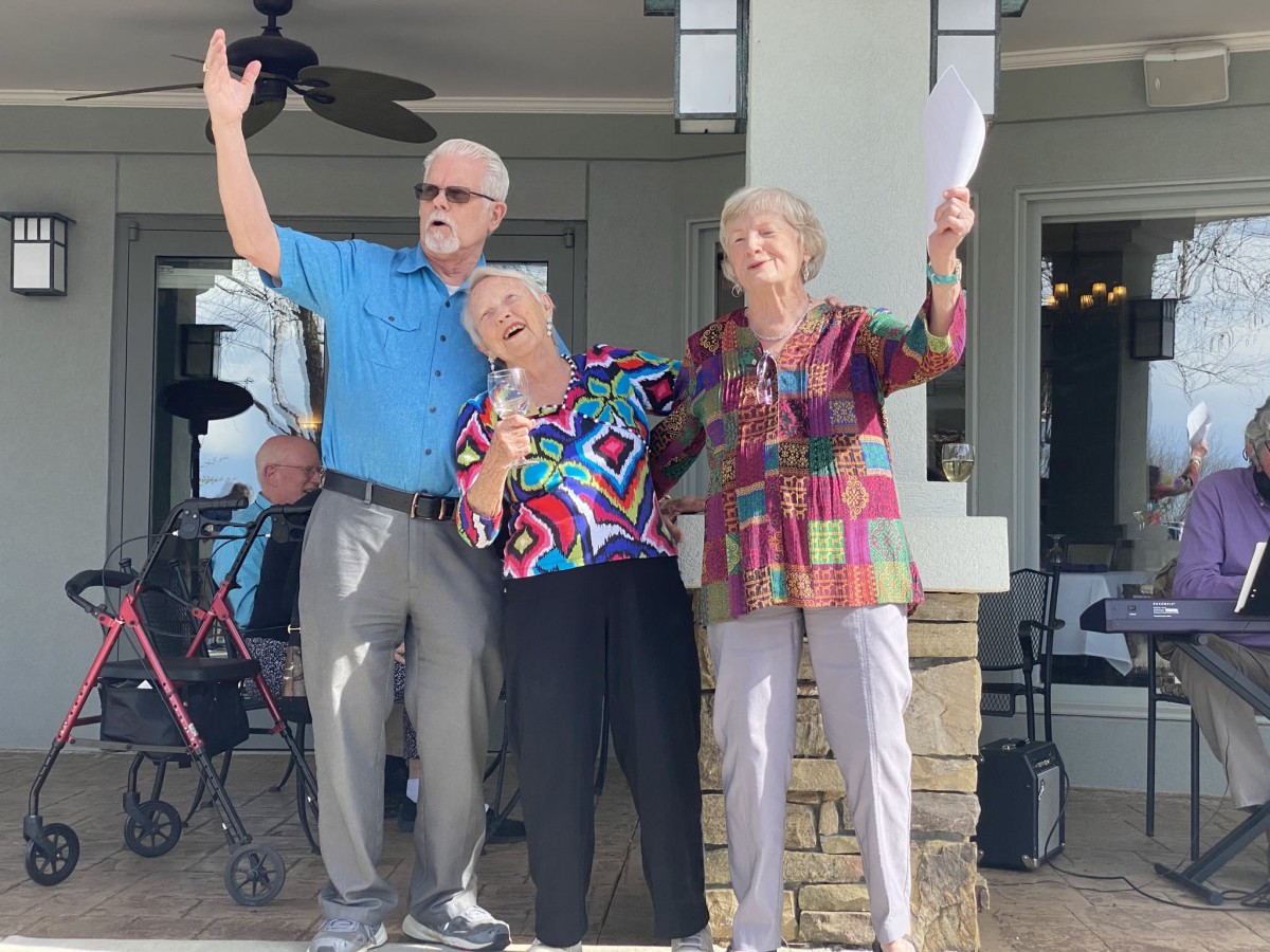 A joyful group of seniors celebrating outdoors with a microphone.