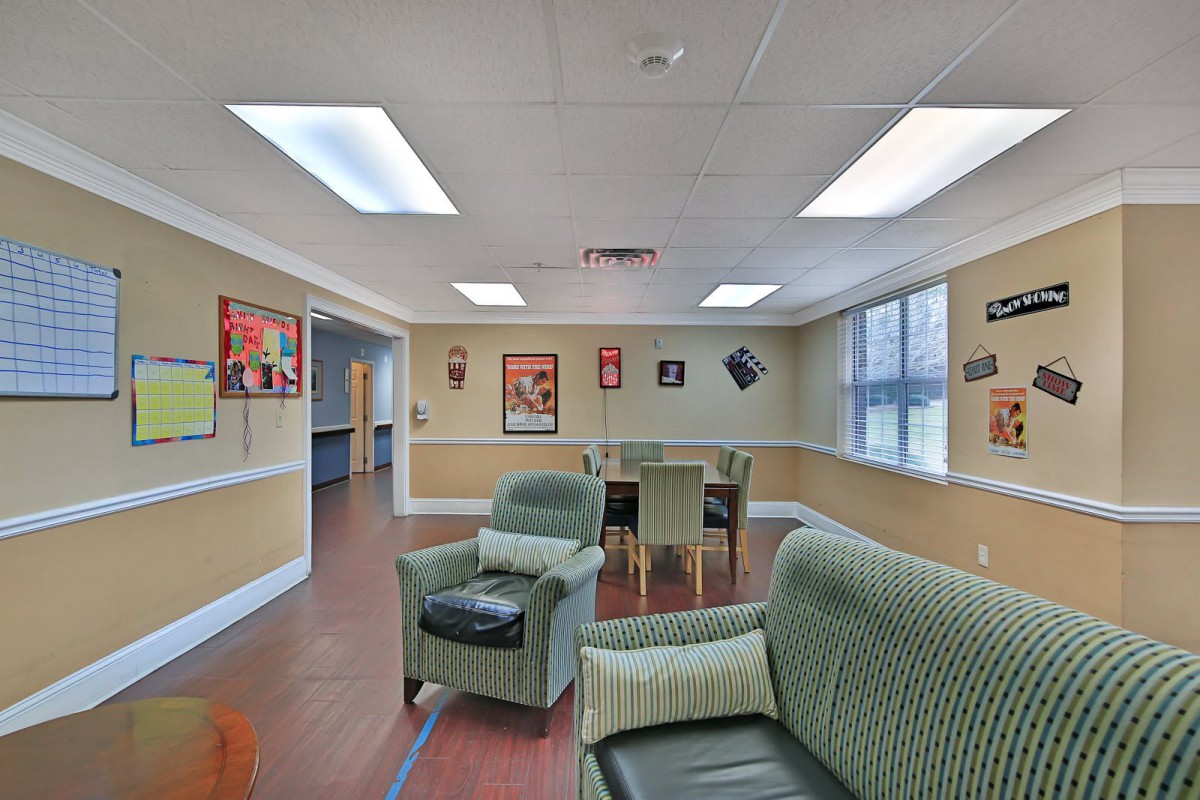A cozy room with comfortable seating and wall posters, illuminated by overhead lights.