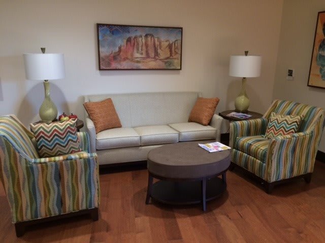 A cozy living room with a sofa, two armchairs, a coffee table, and decorative lamps.