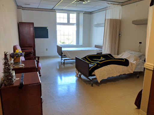 A spacious patient room in a hospital, featuring two beds and essential furniture.
