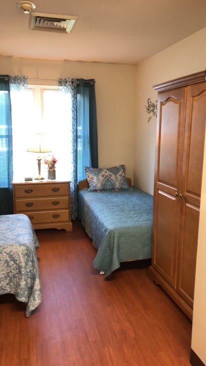 A cozy bedroom with two single beds, a wooden dresser, and a wardrobe.