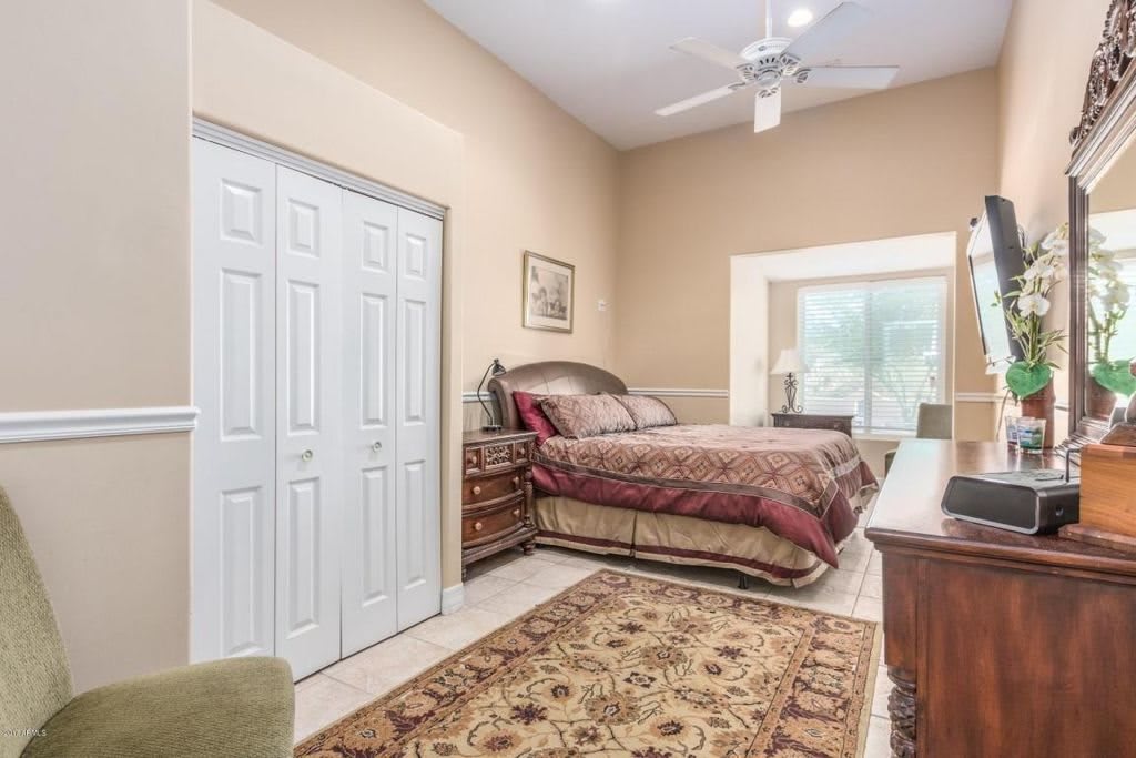 A cozy bedroom with a large bed, closet, ceiling fan, and decorative rug.