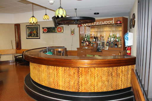 A cozy bar interior featuring a wooden counter and ambient lighting.