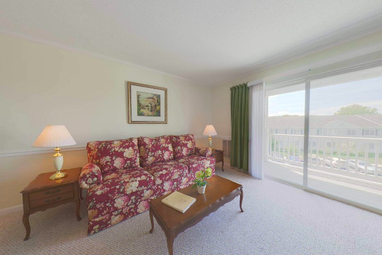 A cozy living room with a floral-patterned sofa, wooden coffee table, and sliding glass doors leading outside.
