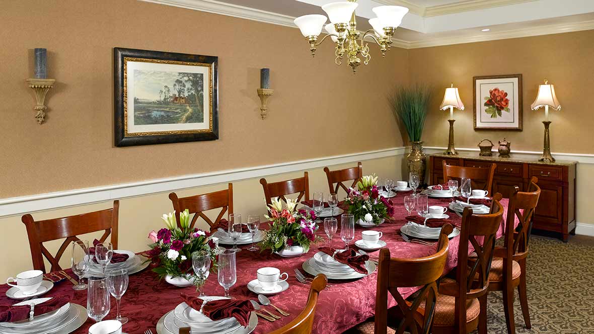 A beautifully set formal dining table with elegant place settings and floral centerpieces under a chandelier.