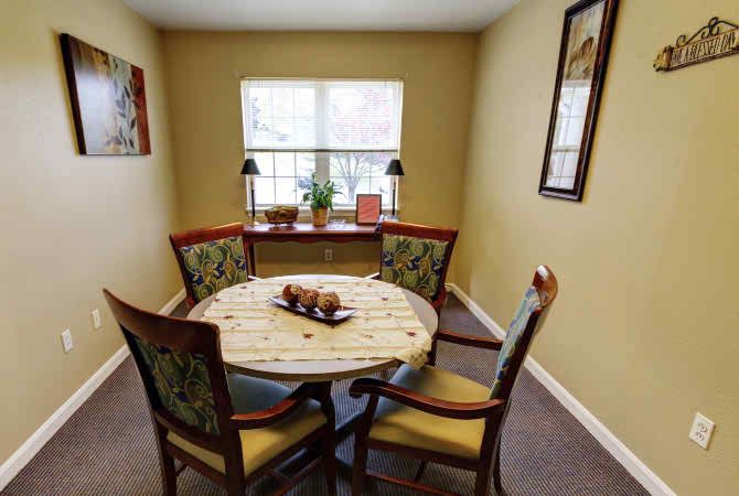 A cozy dining area with a round table and four chairs, decorated with a centerpiece, near a window.