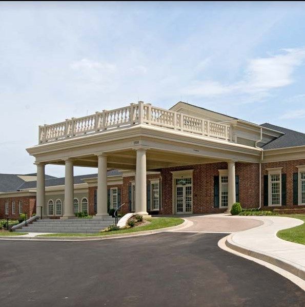 A large brick building with a grand entrance featuring columns and a roundabout driveway.
