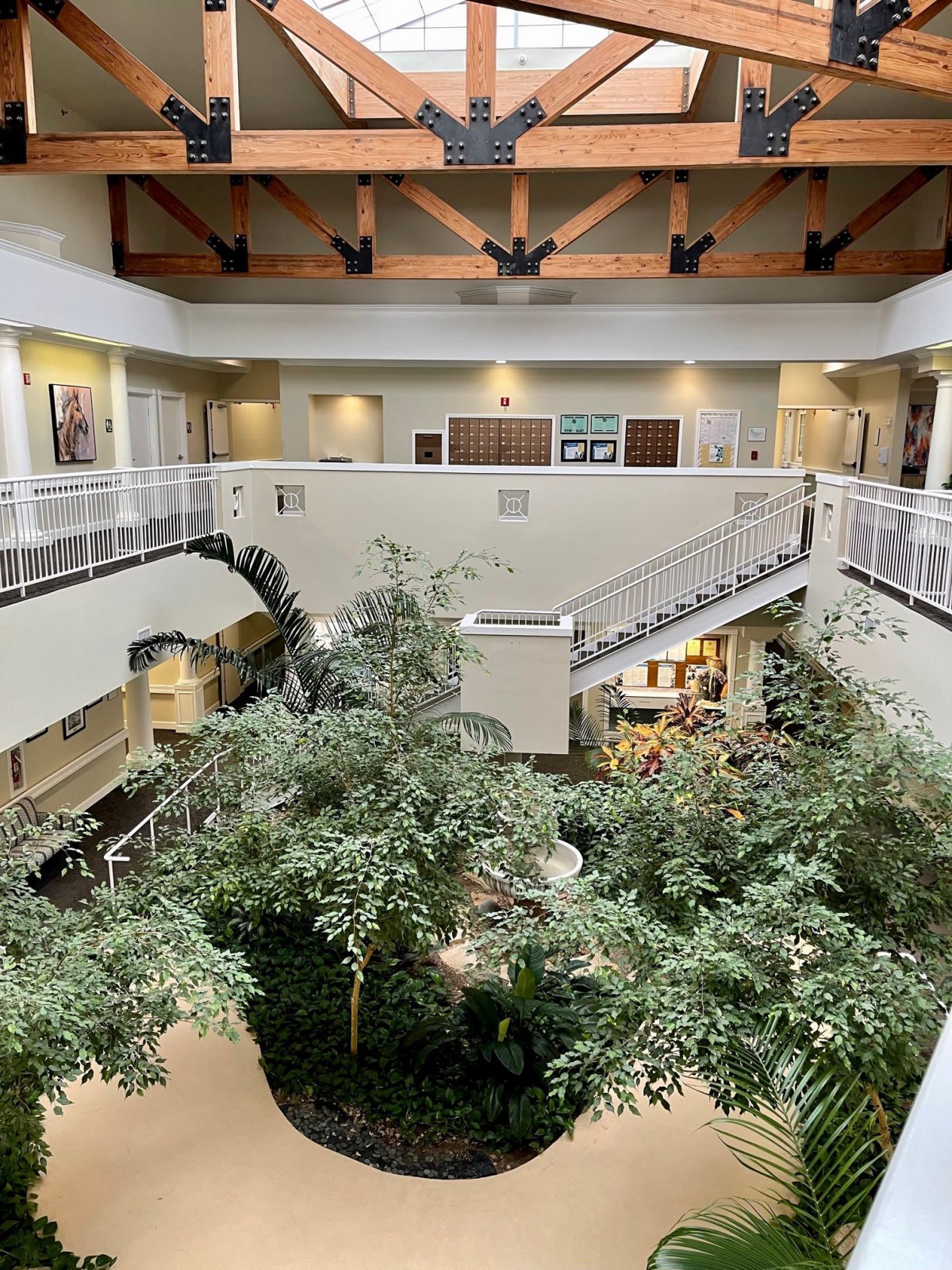A spacious indoor atrium featuring greenery and a central staircase.