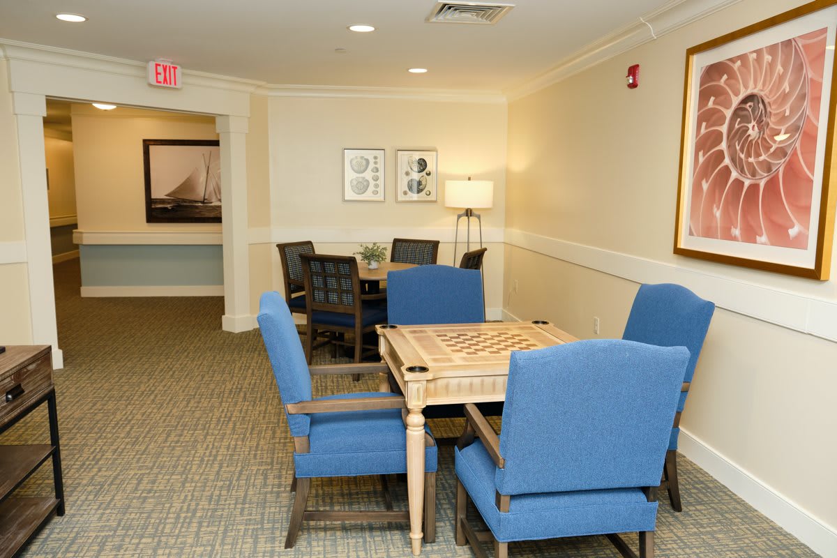 A cozy indoor game room with a board game table and plush blue chairs.