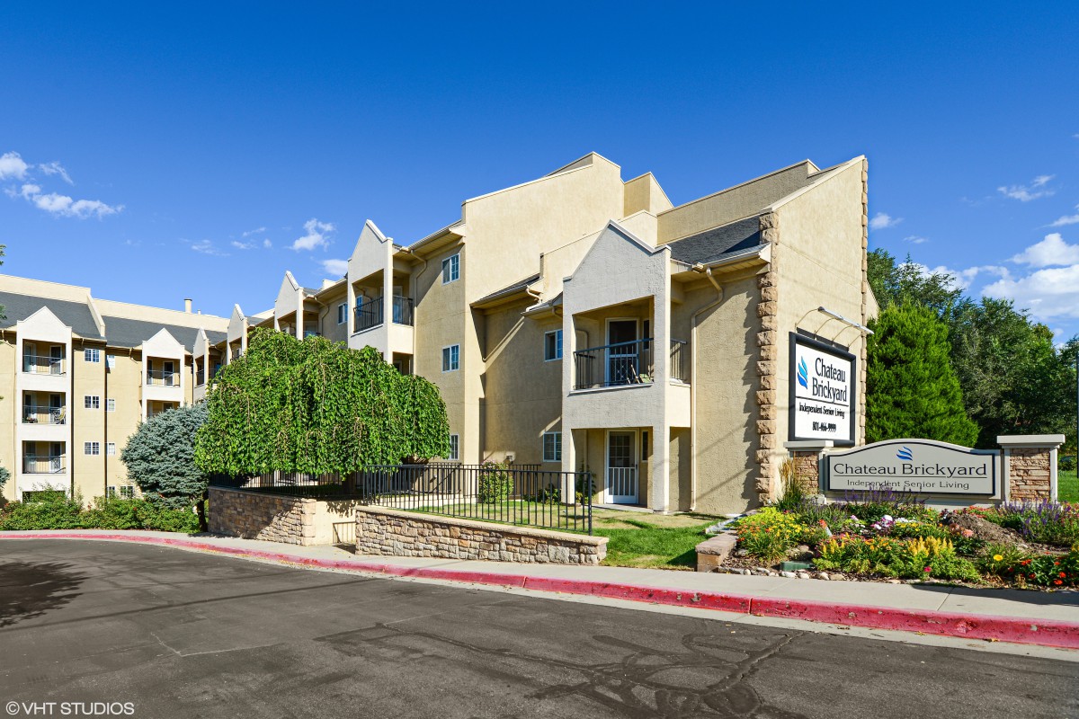 A modern apartment building with a unique architectural design, surrounded by trees and featuring clear signage.