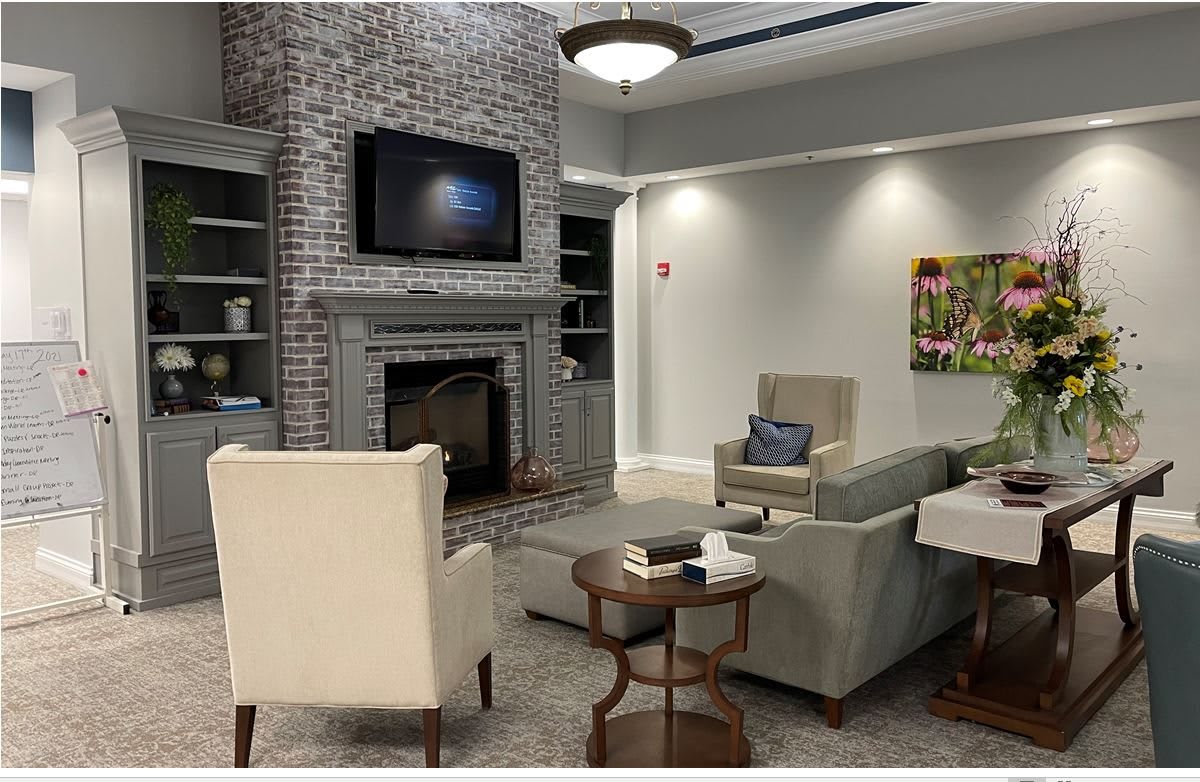A cozy living room featuring a brick fireplace, wall-mounted television, comfortable seating, and elegant decor.