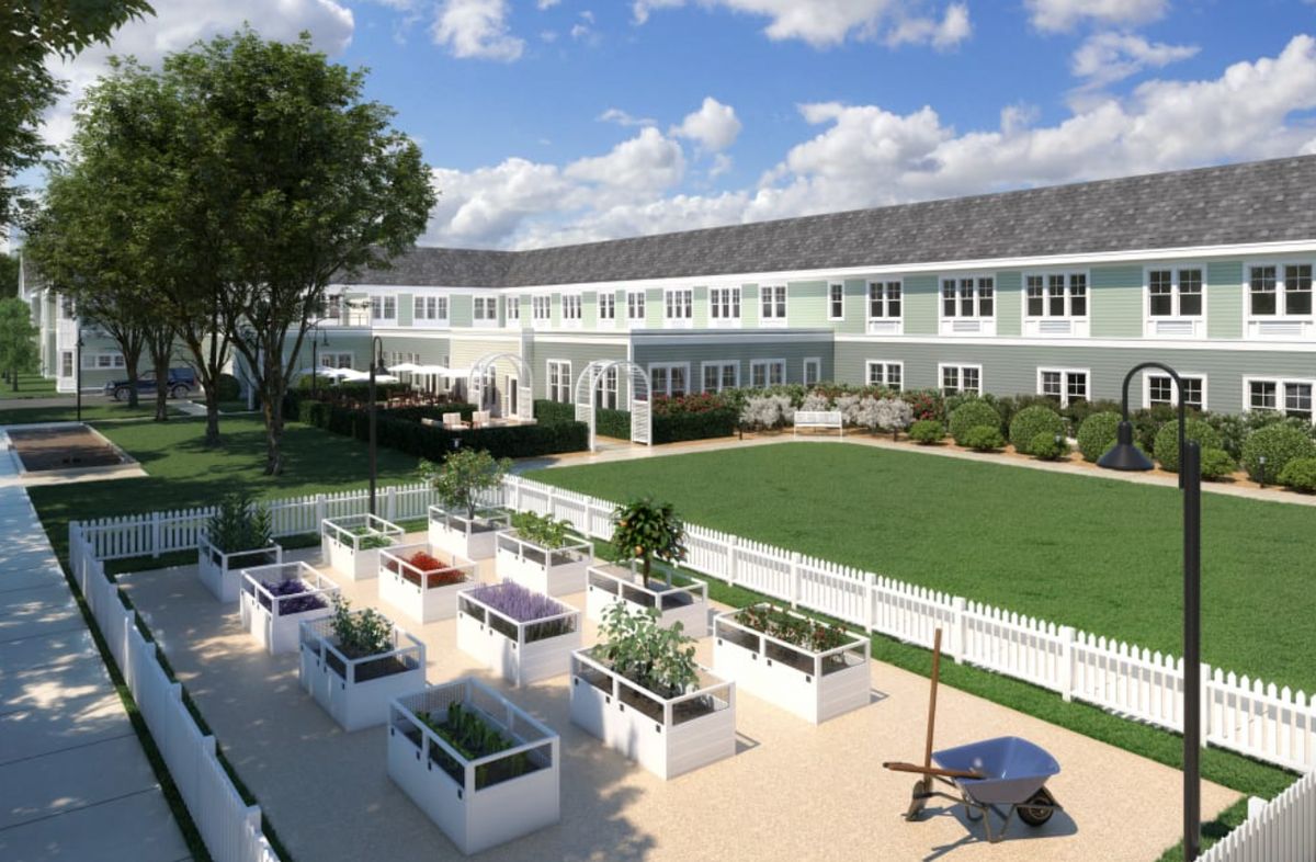 A spacious residential building with a well-maintained garden and outdoor seating area under a clear blue sky.