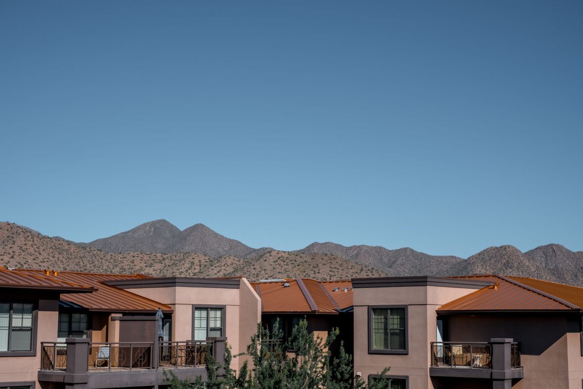 Modern houses with a mountain backdrop under a clear blue sky.