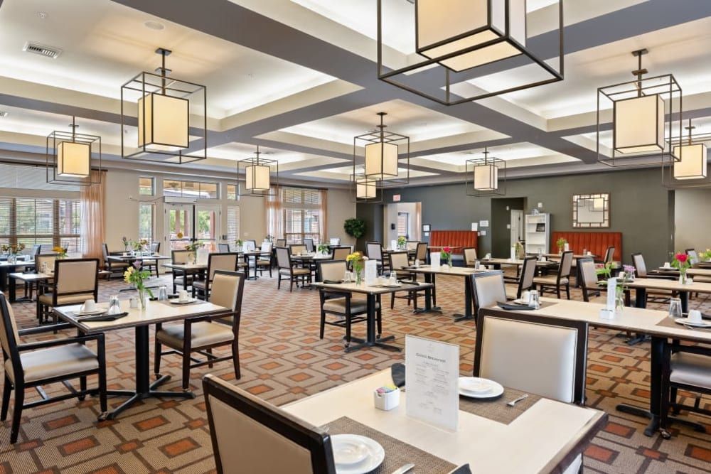 A modern and elegantly designed restaurant dining area with empty tables and chairs, featuring distinctive lighting fixtures.