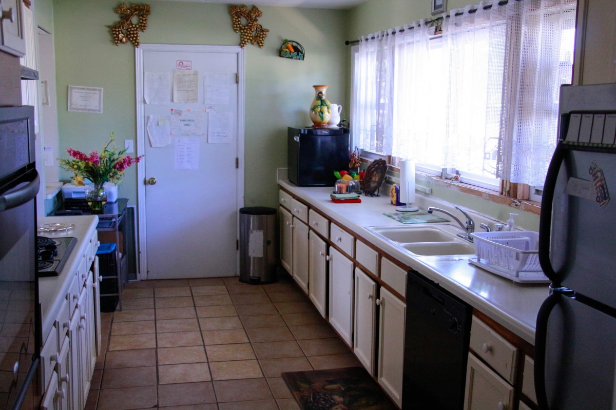 A cozy kitchen with tiled flooring, wooden cabinets, and natural light coming through the window.
