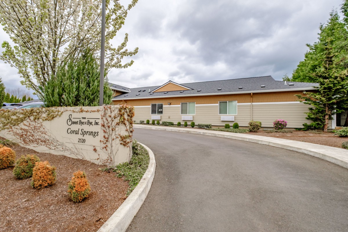 A building with a driveway surrounded by trees under an overcast sky.